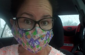 Woman in her forties wearing a fluffy jumper, care bears face mask and matching brooch. She looks bewildered about her fashion choice